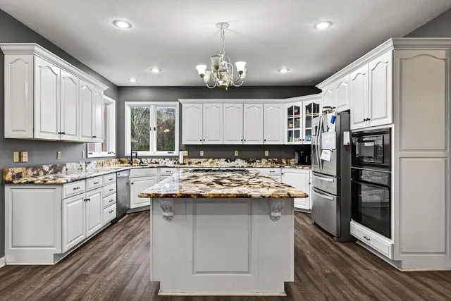 a kitchen with kitchen island granite countertop a sink cabinets stainless steel appliances and a counter top space