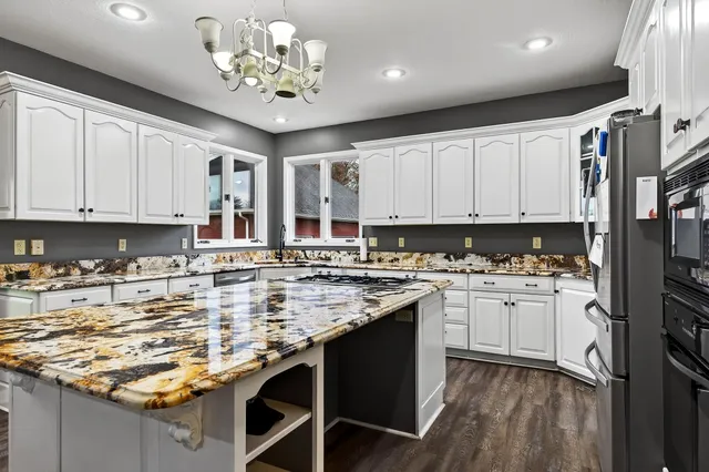 a kitchen with kitchen island granite countertop a sink stove and cabinets