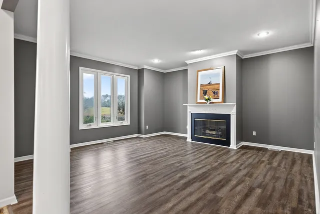 a view of an empty room with wooden floor and a fireplace