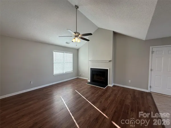 an empty room with windows fireplace and wooden floor