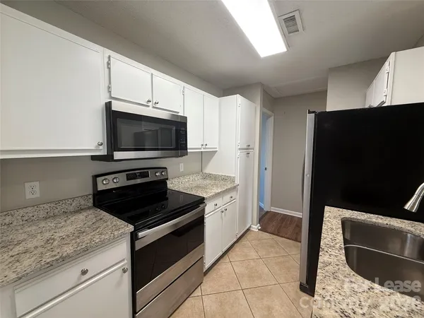 a kitchen with stainless steel appliances kitchen island granite countertop a stove and a microwave