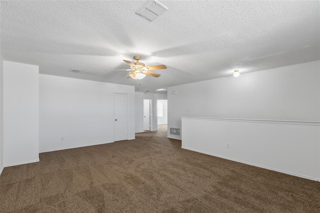 1628 Fieldstone Drive Little Elm, TX 75068 - Photo 22 of 32 an empty room with a chandelier fan and windows