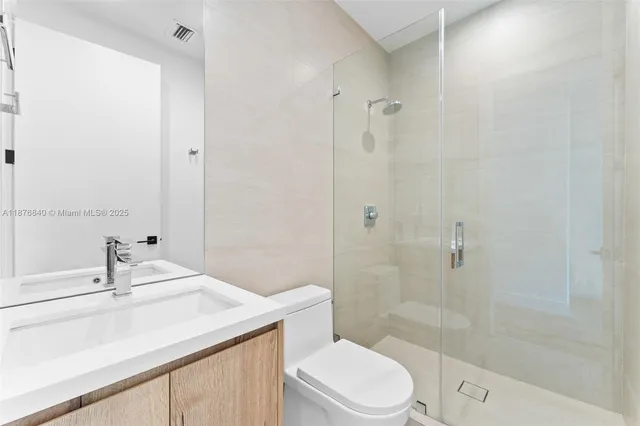 a bathroom with a sink toilet vanity and shower