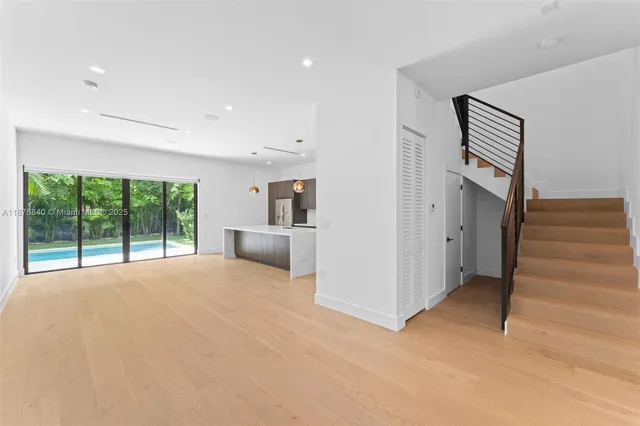 a view of an empty room with a window and a kitchen