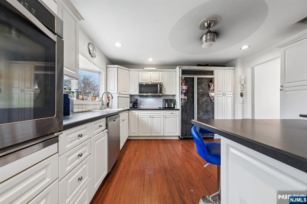 2 Caryn Place Fairfield, NJ 07004 - Photo 6 of 35 a large kitchen with stainless steel appliances granite countertop a lot of counter space and wooden floors