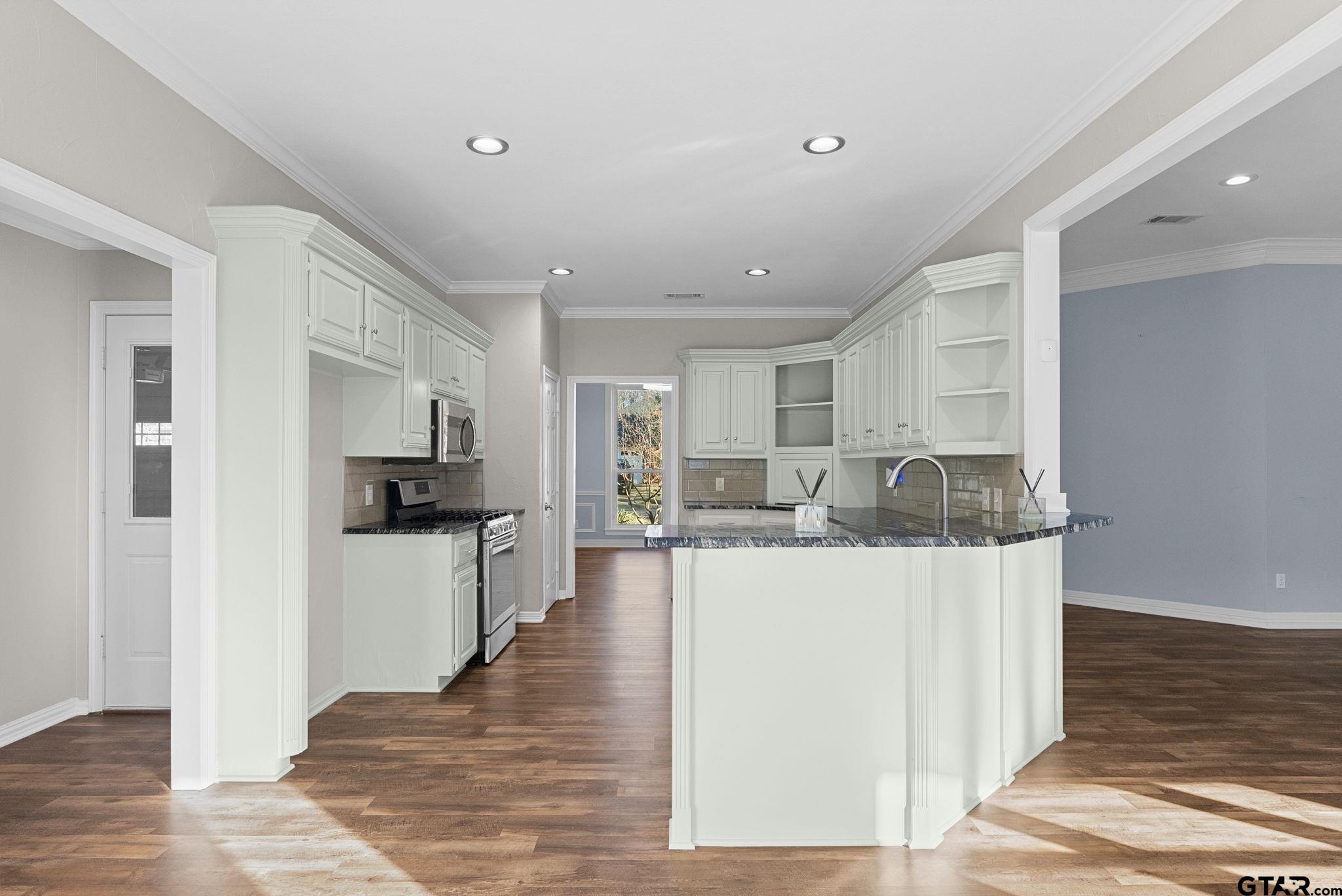 a view of a kitchen with kitchen island stainless steel appliances refrigerator stove microwave and cabinets