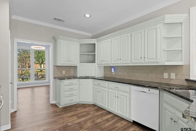 a kitchen with granite countertop white cabinets and wooden floor
