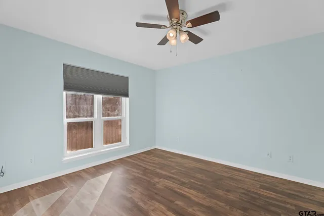 an empty room with a window and ceiling fan