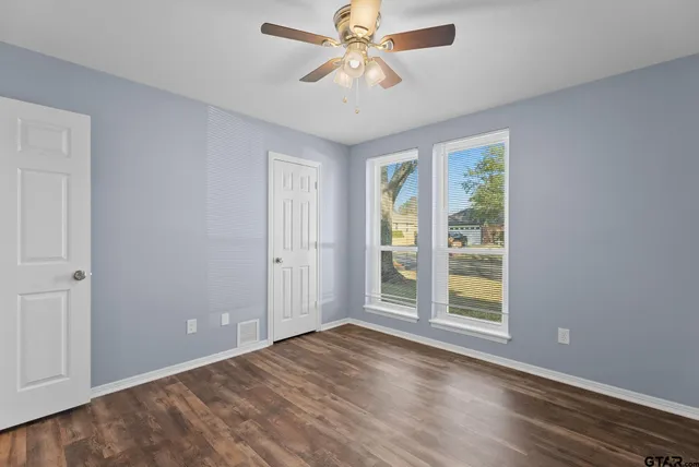 an empty room with windows and ceiling fan
