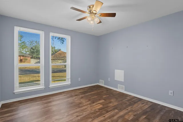 a view of empty room with wooden floor and fan
