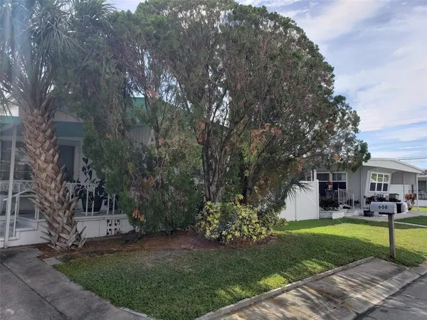 a view of house in front of a big yard with large trees