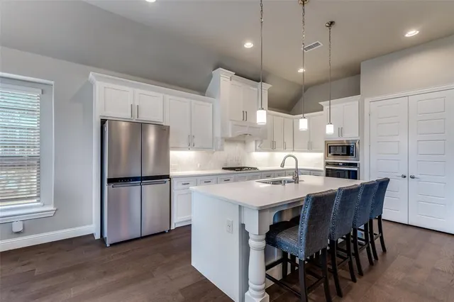 a kitchen with a white center island a sink stainless steel appliances and cabinets