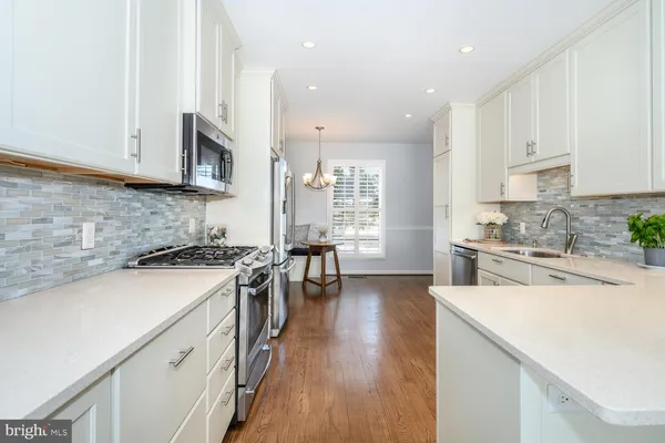a kitchen with stainless steel appliances white cabinets sink and wooden floor