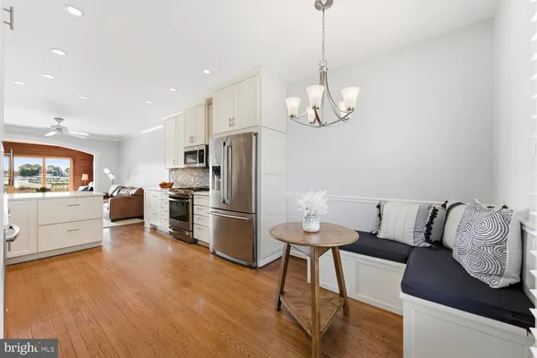 a kitchen with stainless steel appliances kitchen island granite countertop a refrigerator a stove and white cabinets with wooden floor