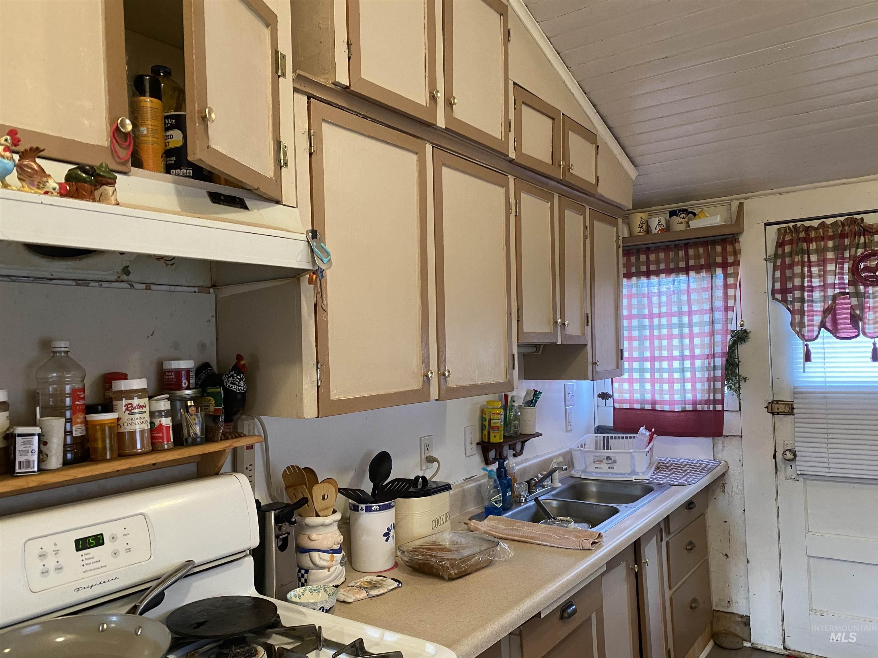 502 East Court Street Weiser, ID 83672 - Photo 4 of 17 Kitchen with gas range gas stove, vaulted ceiling, light countertops, light brown cabinets, and under cabinet range hood