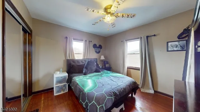 a bedroom with a bed dresser and wooden floor