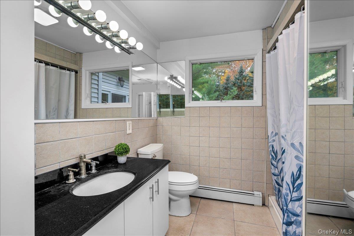 54 Allapartus Road Ossining, NY 10562 - Photo 18 of 24 a bathroom with a granite countertop sink a toilet a mirror and shower