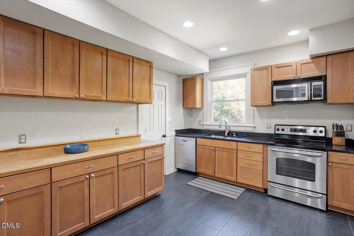807 East Edenton Street Raleigh, NC 27601 - Photo 23 of 68 a kitchen with stainless steel appliances granite countertop a sink a stove a microwave and wooden cabinets