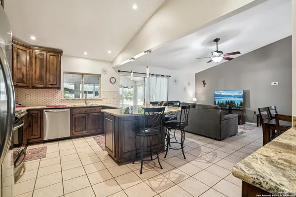 a kitchen with stainless steel appliances kitchen island granite countertop a table chairs sink and cabinets