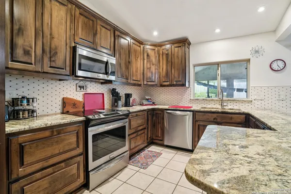 a kitchen with stainless steel appliances granite countertop a stove a sink and a microwave