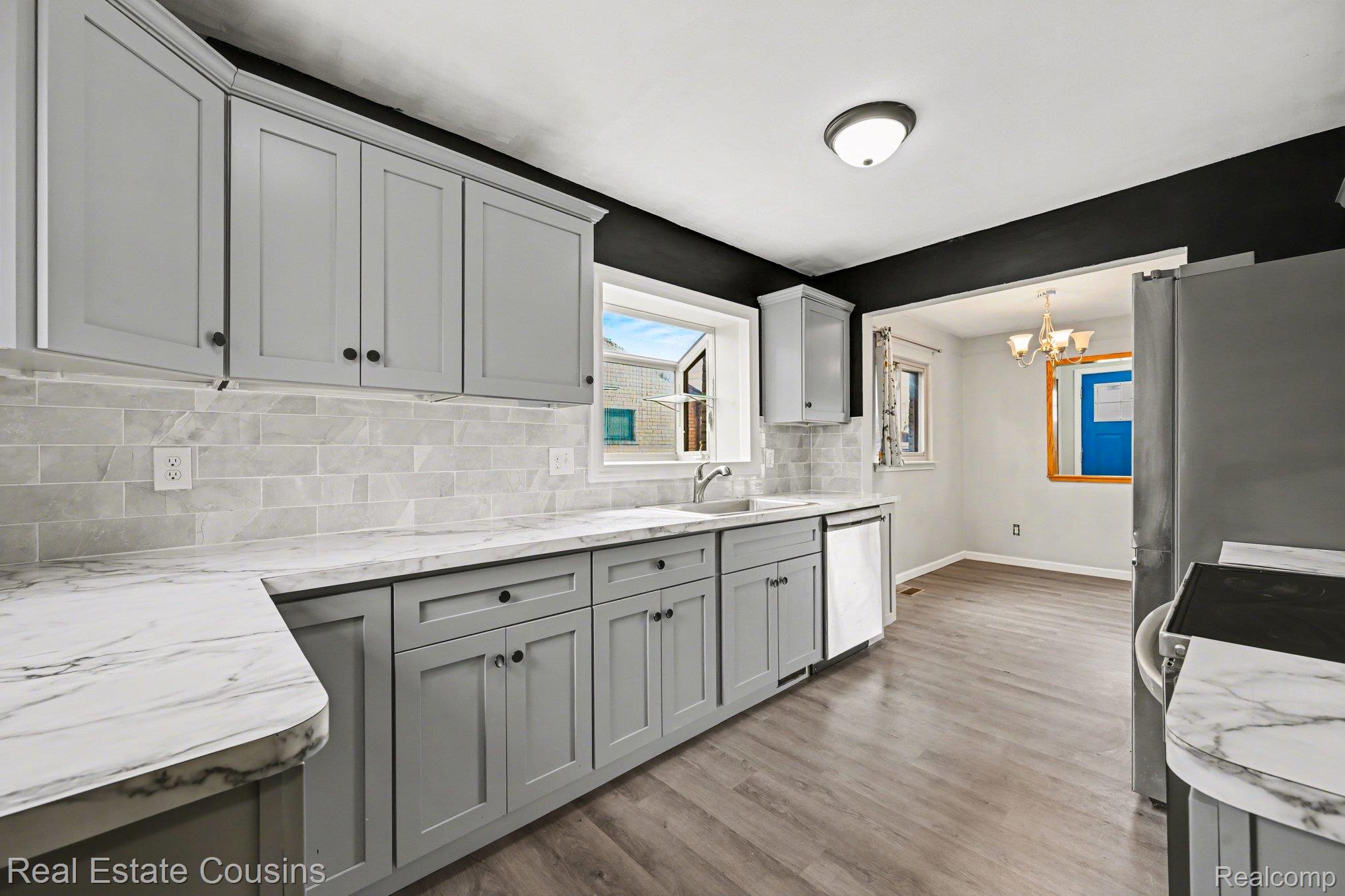 32224 Joy Road Livonia, MI 48150 - Photo 8 of 33 Kitchen with backsplash, light wood-type flooring, gray cabinets, stainless steel appliances, and suspended lighting