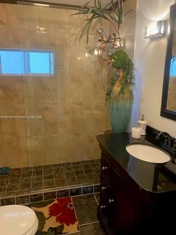 a bathroom with a granite countertop sink a toilet a mirror and vanity