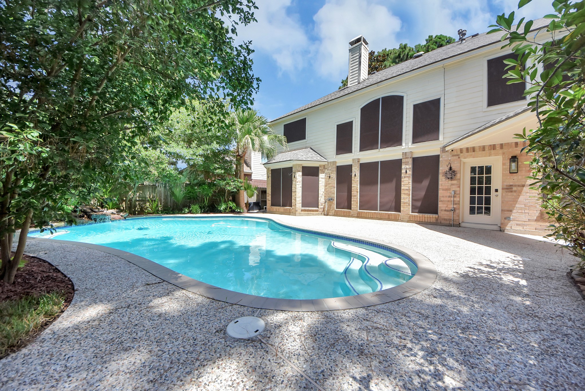 7522 Tumbling Road Humble, TX 77346 - Photo 39 of 48 A serene backyard oasis featuring a sparkling pool surrounded by lush greenery and mature trees, perfect for relaxation and outdoor enjoyment.