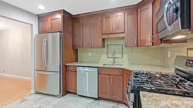 a kitchen with stainless steel appliances granite countertop a refrigerator stove and sink