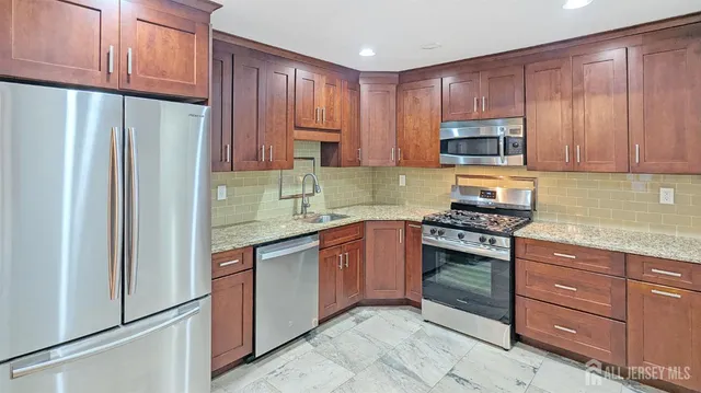 a kitchen with granite countertop wooden cabinets and stainless steel appliances