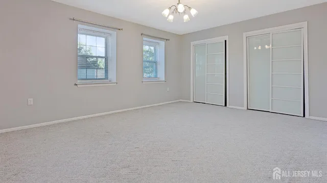 an empty room with windows and chandelier fan