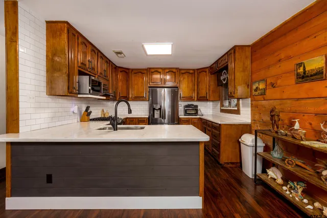 a kitchen with granite countertop wooden cabinets a refrigerator stove top oven and sink