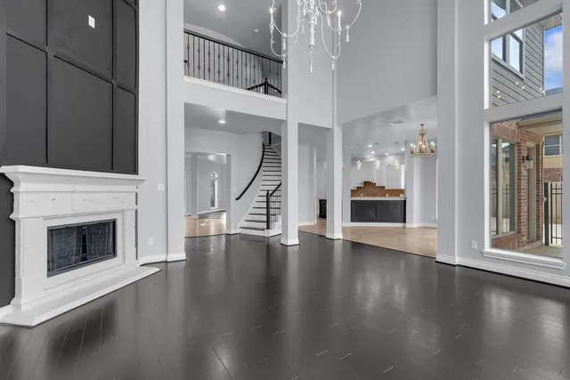 an empty room with wooden floor fireplace and windows