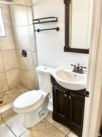 570 250 East Parowan, UT 84761 - Photo 9 of 27 Bathroom featuring a dark wood-finish vanity with an integrated sink, a matching framed mirror, and a tile-surround shower with a bronze-finish fixture