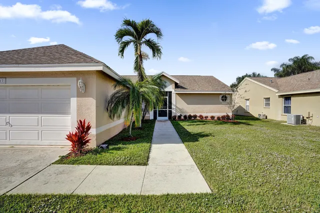 a front view of a house with a garden and trees