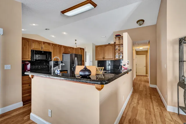 a kitchen with stainless steel appliances granite countertop a sink a stove cabinets counter space and a window