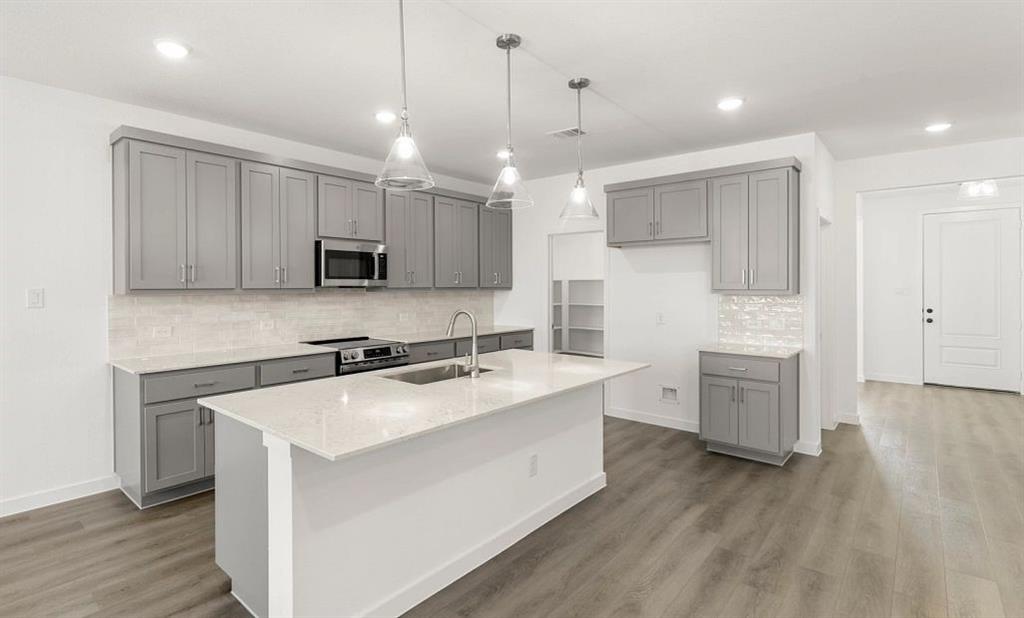 1008 Colgate Circle Princeton, TX 75407 - Photo 12 of 29 a kitchen with a sink a stove a refrigerator and white cabinets