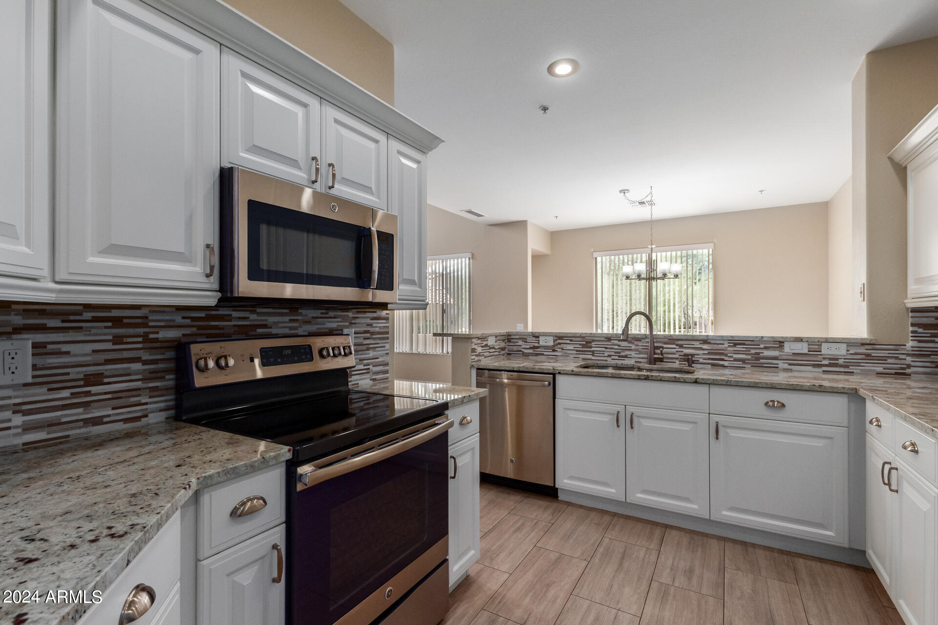 a kitchen with stainless steel appliances granite countertop a stove top oven a sink dishwasher and a microwave oven with large wooden cabinets