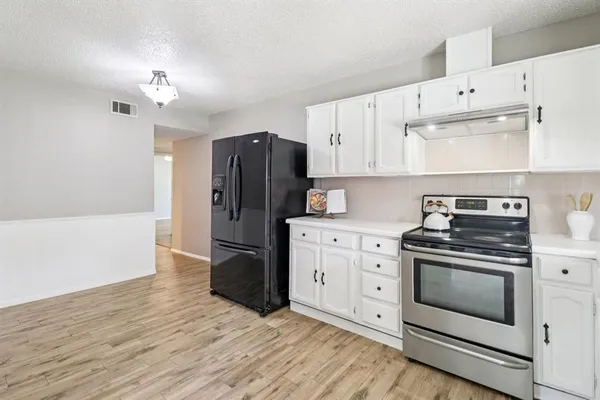 a kitchen with a stove white cabinets and stainless steel appliances