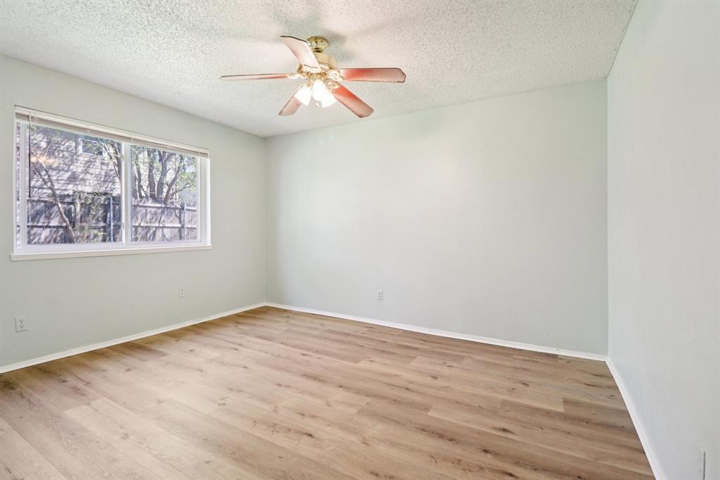 3216 Red Oak Lane Bedford, TX 76021 - Photo 20 of 40 an empty room with wooden floor chandelier fan and windows