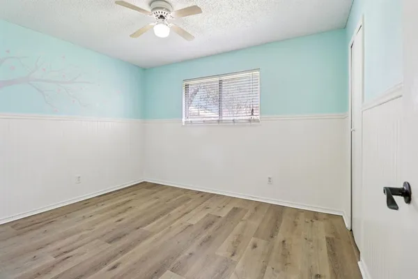 an empty room with a window and a ceiling fan