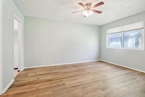 a view of an empty room with window and a ceiling fan