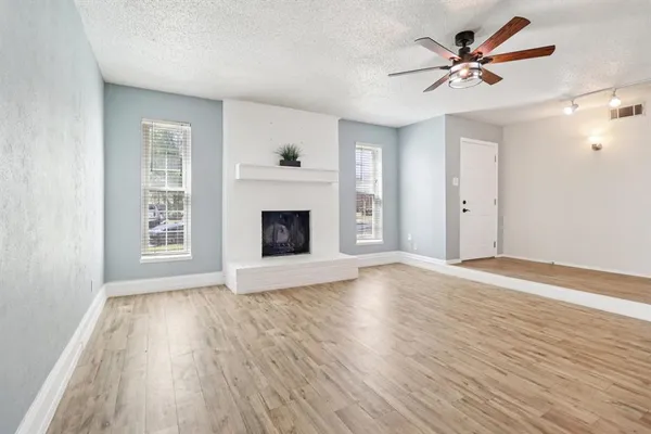 a view of an empty room with wooden floor and a fireplace