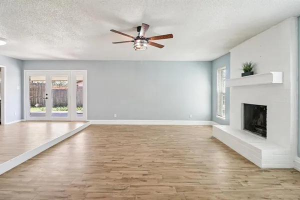 a view of an empty room with glass door and chandelier fan