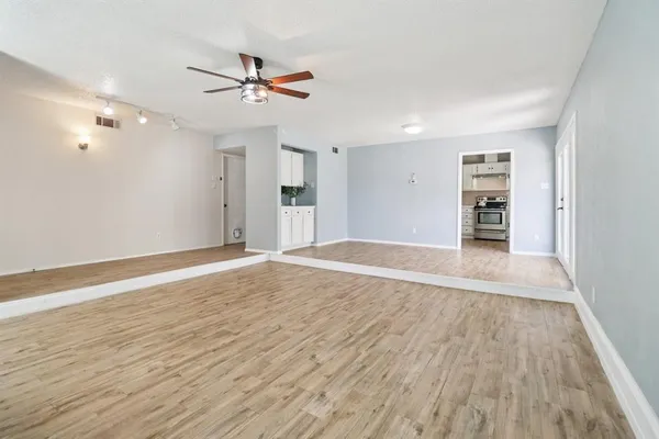 a view of an empty room with wooden floor closet and a ceiling fan