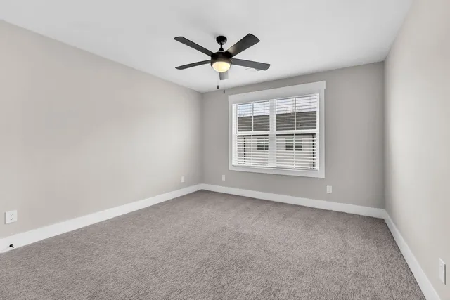 an empty room with window and ceiling fan