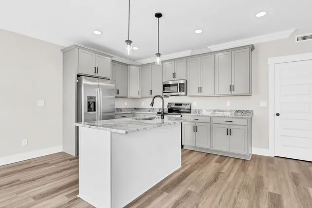 a kitchen with kitchen island a white counter top space cabinets and stainless steel appliances