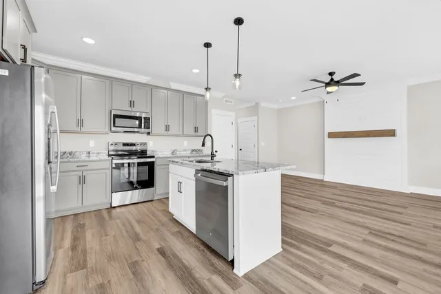 a kitchen with stainless steel appliances a stove a sink dishwasher a refrigerator and a stove with wooden floors