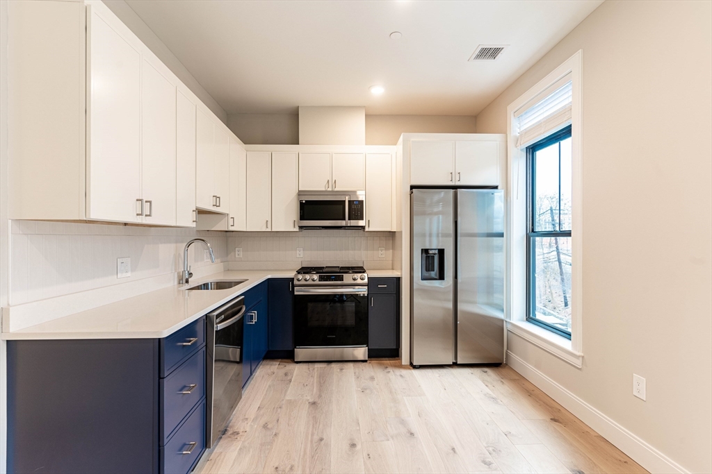 157 Everett Street, Unit 301 Boston, MA 02134 - Photo 2 of 9 a kitchen with stainless steel appliances granite countertop a refrigerator stove top oven and sink