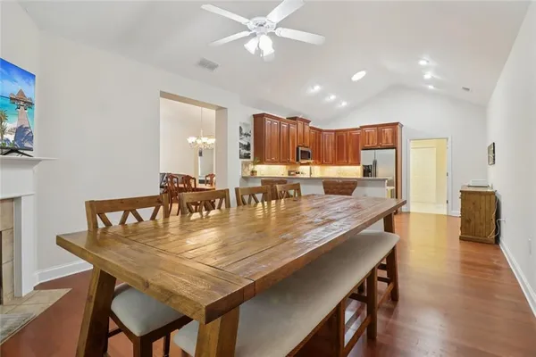 a kitchen with kitchen island a dining table chairs refrigerator and cabinets