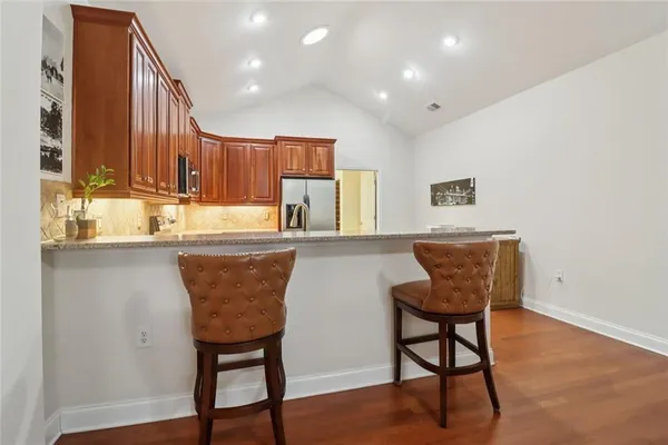 a kitchen with stainless steel appliances granite countertop a refrigerator a sink dishwasher a stove with wooden cabinets and a refrigerator